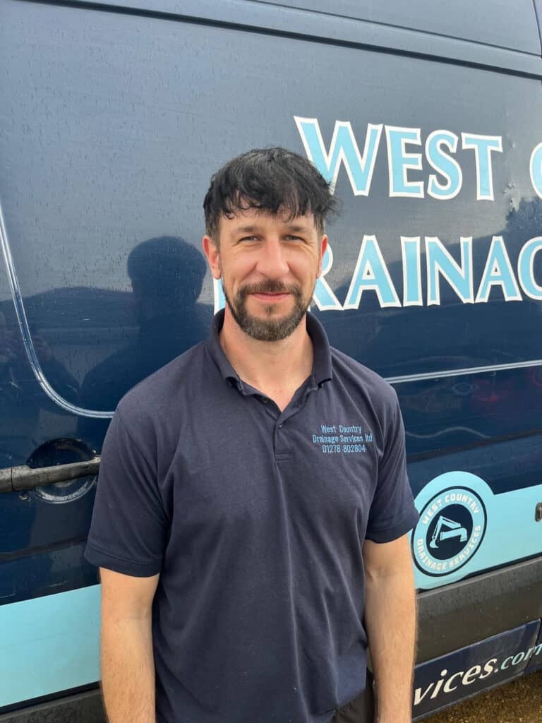 Professional man standing in front of drainage service vehicle.